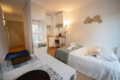 a room with two beds and a table and a kitchen at Cocon Urbain - Près de la Gare in Nice
