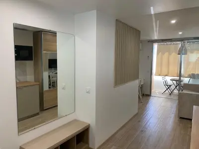 a living room with white walls and a wooden floor at Azur & Chill - à proximité Mer Train Bus Aéroport in Saint-Laurent-du-Var