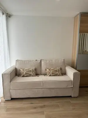 a couch in a living room with two pillows on it at Azur & Chill - à proximité Mer Train Bus Aéroport in Saint-Laurent-du-Var