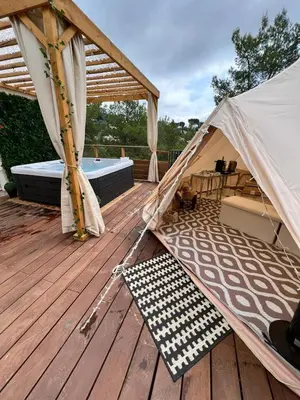 a tent on a deck with a dog laying on a rug at LOVE ROOM Tente chauffée Lodge spa MFG chez C&C, exclusivement réservée aux ADULTES in Cantaron