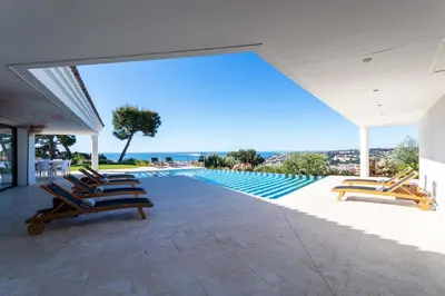 a swimming pool with lounge chairs and the ocean at VILLA ADRIANA VI4411 By Riviera Holiday Homes in Nice