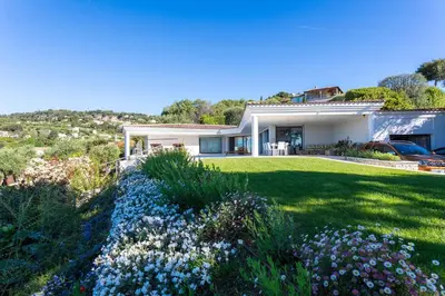 a white house with a yard with flowers at VILLA ADRIANA VI4411 By Riviera Holiday Homes in Nice