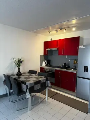 a kitchen with red cabinets and a table and a refrigerator at Californie in Nice
