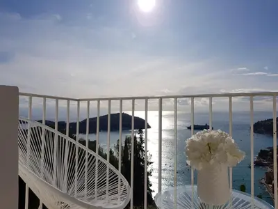 a white chair with a vase of flowers on a balcony at 73 CORNE D OR - Duplex plein SUD, VUE MER, BALCON in Villefranche-sur-Mer