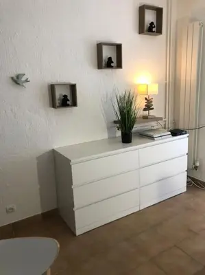a white dresser with a lamp and a plant on it at Le Rabelais, Studio terrasse in Nice