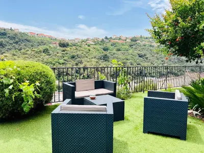 a garden with two chairs and a bench on the grass at Nissa la bella, Piscine et vue mer in Nice