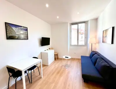 a living room with a blue couch and a table at Collet Résidence in Nice