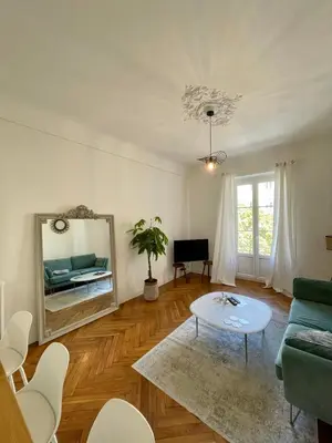 a living room with a couch and a mirror at Appartement niçois au coeur du triangle d'or in Nice