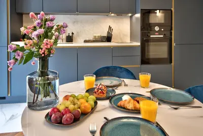 a table with plates of food and a vase of flowers at Aparthotel 9 ALBERTI Nice Centre in Nice