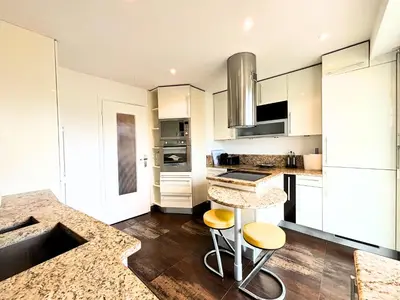 a kitchen with white cabinets and a counter with stools at Le St Charles in Saint-Laurent-du-Var