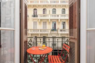 a red table and chairs on a balcony with a building at Soleil de la Buffa - Un joyau central à 3 min des plages in Nice
