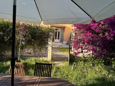 a table with an umbrella in a garden with flowers at STUDIO dans Villa à Nice Ouest in Nice