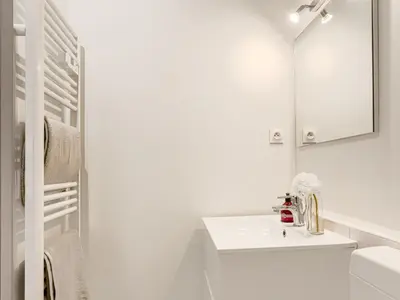 a white bathroom with a sink and a mirror at Studio Le Maréchal by Interhome in Nice