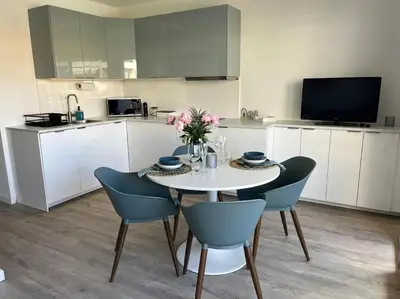 a kitchen with a table with blue chairs and a white table at New apartment with swimming pool in Beaulieu-sur-Mer