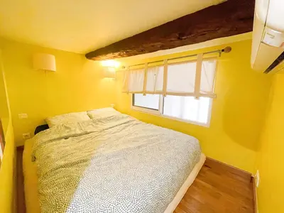 a small yellow bedroom with a bed and a window at Charmant appartement atypique au coeur du Vieux-Nice in Nice