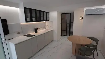 a kitchen with white counters and a wooden table at Club Inn Appartement in Nice