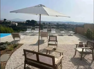 a group of chairs and an umbrella on a patio at DOMAINE LOU BEL AZUR - Harmonie in Saint-Laurent-du-Var