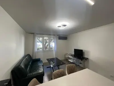 a living room with a black leather couch and a table at Port Lympia - Grand 2 Pièces Confort in Nice