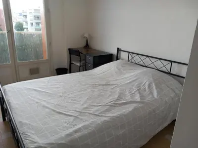 a bedroom with a bed with a white comforter at Appartement cosy Nice in Nice