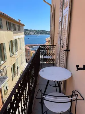 a table and chairs on a balcony with a view of the water at Blue House in Villefranche-sur-Mer