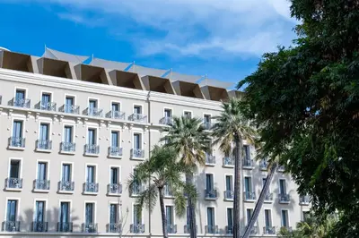 a white building with palm trees in front of it at Maison Albar - Le Victoria in Nice
