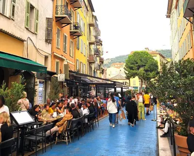 a group of people sitting at tables in a street at Jolie deux pièces au cœur de Nice in Nice