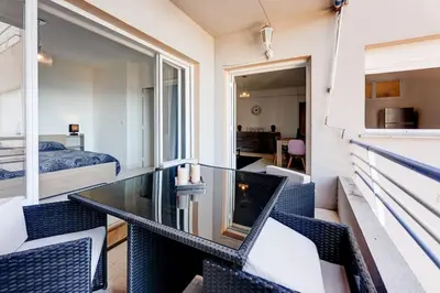 a balcony with a glass table and chairs at face à la mer in Cros-de-Cagnes