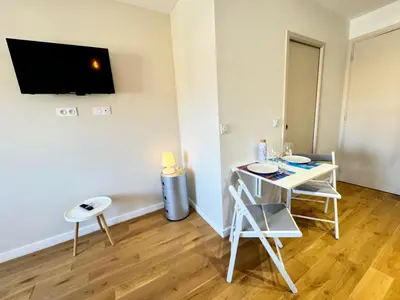 a small room with a table and a tv on a wall at APartHotel Riviera - COCON DE LA LIBERTE - Grimaldi - Promenade des Anglais in Nice