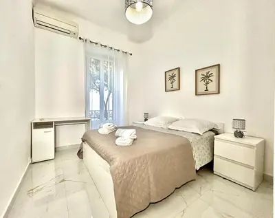 a white bedroom with a bed and a window at Charmant 4 pièces - Cour privative - Port de Nice in Nice