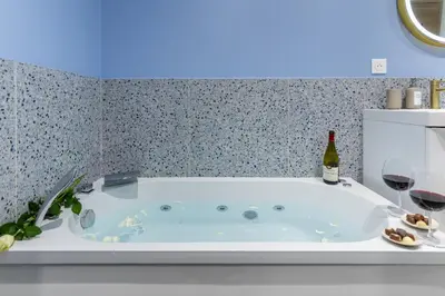 a bath tub with a bottle of wine and two glasses at Lavie Maison Sauna and Hot Tub Seaside in Nice