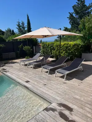 a row of lounge chairs and an umbrella next to a pool at Superbe villa piscine proche ville et mer au calme in Nice