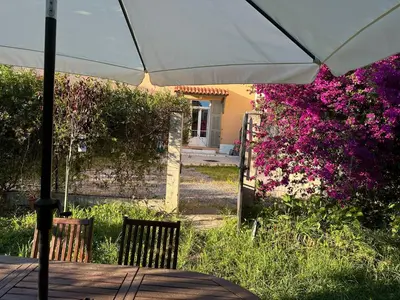 a table with an umbrella in a garden with flowers at Maison de ville à Nice Ouest dans propriété arborée in Nice