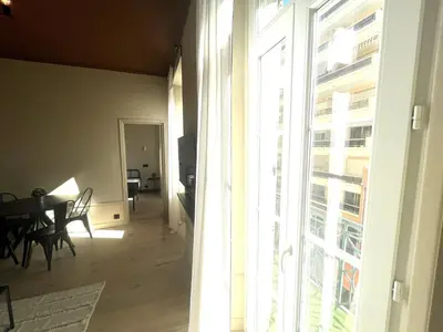 a living room with a table and a window at Beaumont republique in Nice