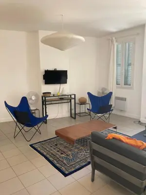 a living room with chairs and a couch and a tv at L'Appartement Bleu in Nice