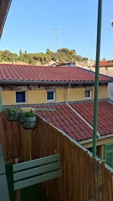 a building with a red roof and two potted plants on a fence at Historic Bright and Beautiful Apartment in Old Nice with Castle Hill View in Nice