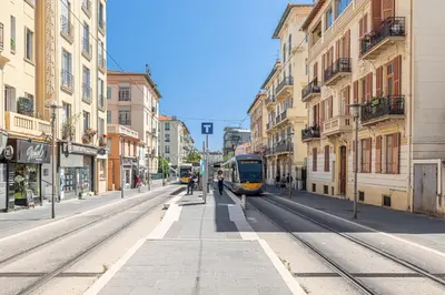 a train on a city street with buildings at Large & Quiet 1 Bdr Downtown in Nice