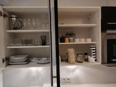 a white pantry with plates and dishes on shelves at La Terrazza in Nice