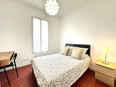 a bedroom with a bed and a desk and a window at Villa Lila in Nice