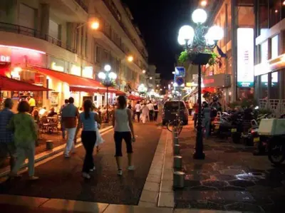a group of people walking down a street at night at Center 2 min walk to beach quiet sunny balcony in Nice