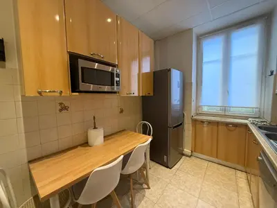 a kitchen with a wooden table and a refrigerator at Spacieux appartement climatisé centre Nice in Nice