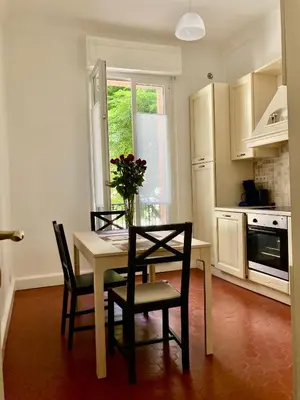 a kitchen with a table with chairs and a vase of flowers at 2P Moderne Riquier proche Port, Gare, Tramway in Nice