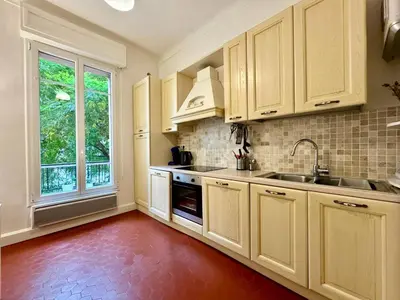 a kitchen with white cabinets and a large window at 2P Moderne Riquier proche Port, Gare, Tramway in Nice