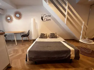 a room with a bed and a table and stairs at Studio moderne climatisé avec coin nuit, proche mer et Hauts de Cagnes in Cagnes-sur-Mer