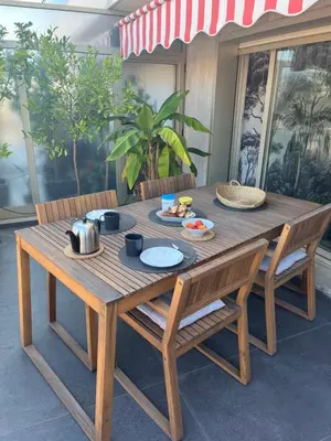 a wooden table with two chairs and a table with food on it at Splendide penthouse au coeur de Nice in Nice