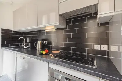 a kitchen with black tiles on the wall at Bohème-Chic au cœur du VIEUX NICE #Lovely in Nice