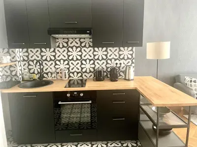 a kitchen with black cabinets and a wooden counter at Superbe Appartement au Cœur de Nice in Nice