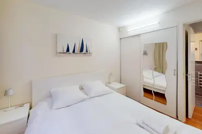 a white bedroom with a white bed and a mirror at Cozy Apt with Balcony - 5 min to the Beach in Nice