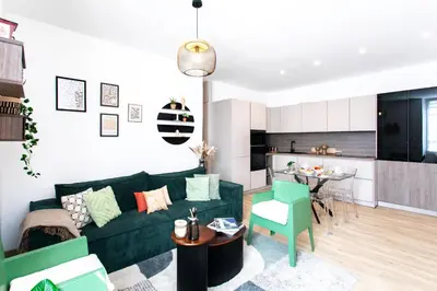 a living room with a green couch and a kitchen at L52 2BDR Massena central, 2 min from the beach AC in Nice