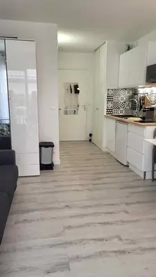 a kitchen with white cabinets and a wooden floor at Tournesol de Nice in Nice
