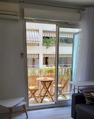 a living room with a sliding glass door with a table at Tournesol de Nice in Nice